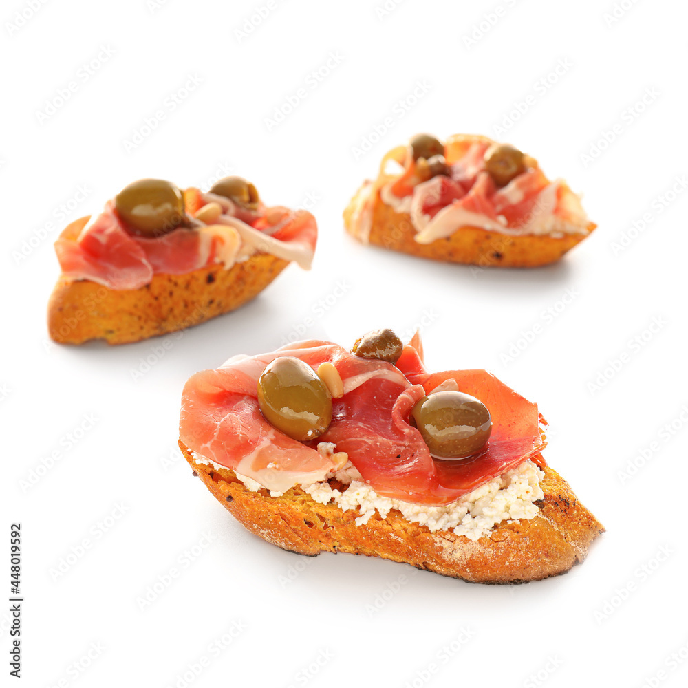 Tasty bruschettas with cheese, prosciutto and olives on white background