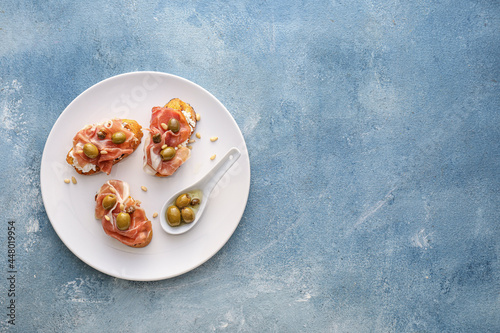 Canvas Print Tasty bruschettas with cheese, prosciutto and olives on color background