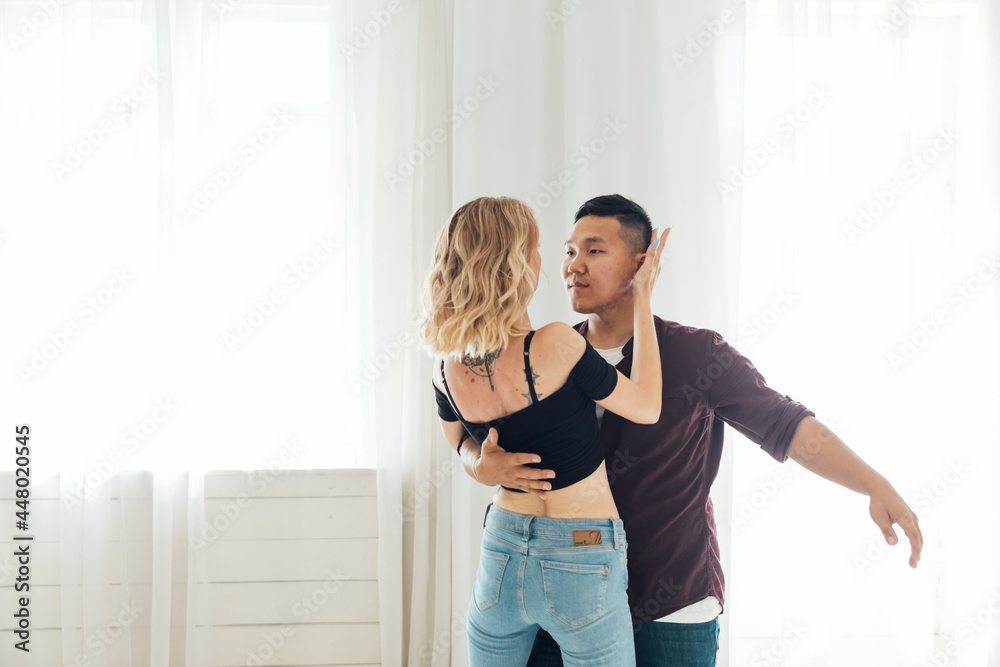 a man and a woman dance bachata to music in a white room a man and a woman dance bachata to music in a white room