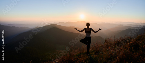 Stampa su tela Panoramic view of woman practicing yoga on background of evening mountains