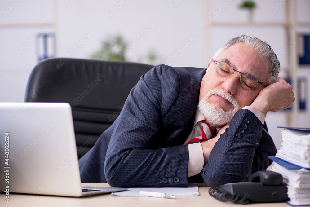 Old male employee sitting at workplace Old male employee sitting at workplace
