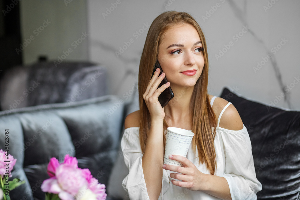 Young smiling woman talking on cell phone at home