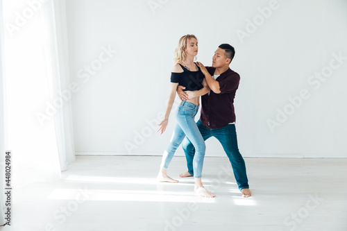 a man and a woman dance bachata to music in a white room
