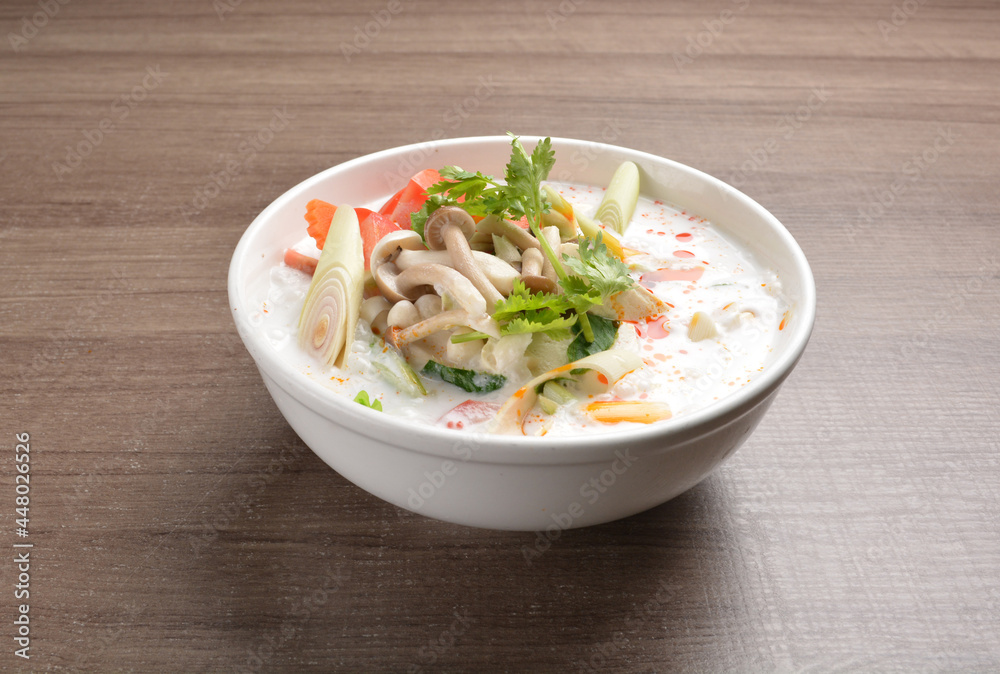 cook hot and spicy white coconut curry laksa soup with mushroom and mixed vegetables in white bowl on wood background asian halal vegan menu cook hot and spicy white coconut curry laksa soup with mushroom and mixed vegetables in white bowl on wood background asian halal vegan menu