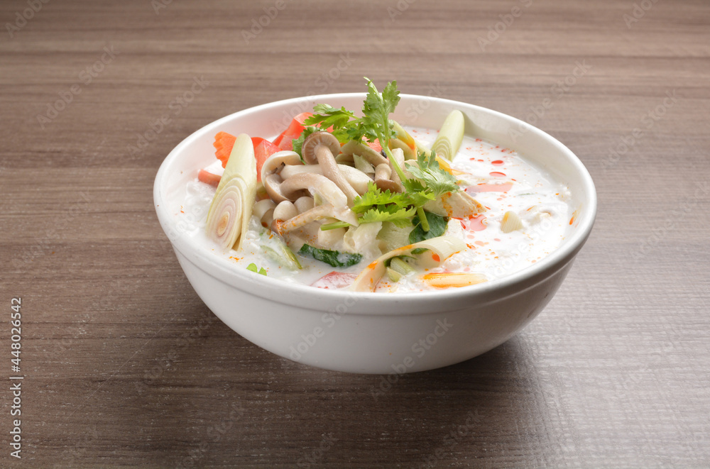 cook hot and spicy white coconut curry laksa soup with mushroom and mixed vegetables in white bowl on wood background asian halal vegan menu cook hot and spicy white coconut curry laksa soup with mushroom and mixed vegetables in white bowl on wood background asian halal vegan menu