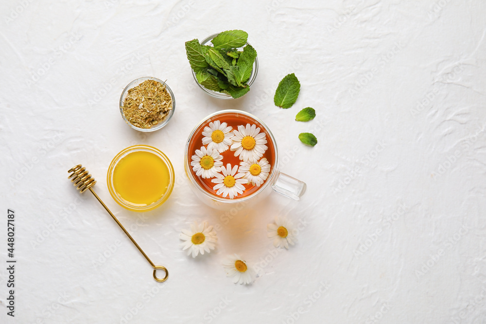 Composition with cup of chamomile tea, flowers, mint and honey on light background Composition with cup of chamomile tea, flowers, mint and honey on light background