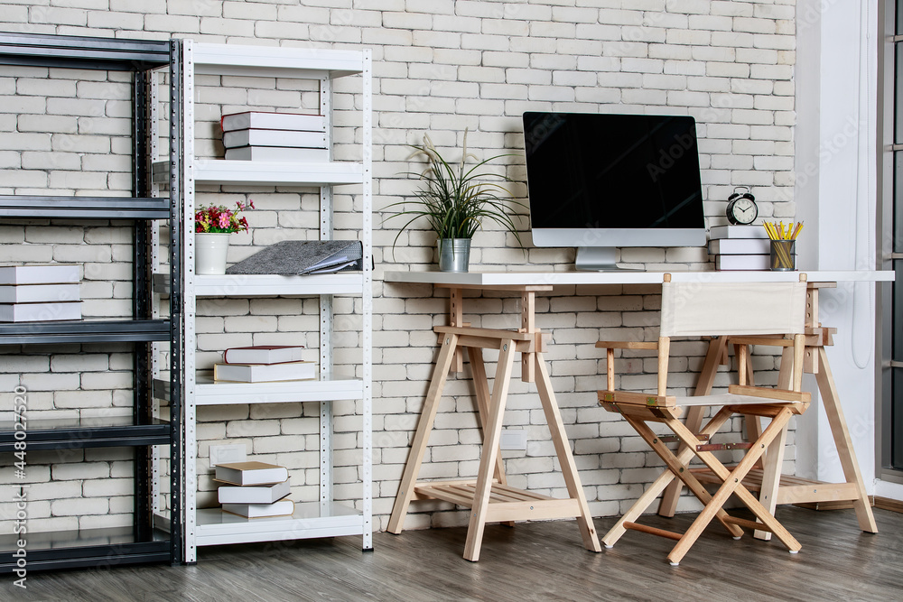 Minimal style with less decorate office coner with metal shelf, computer director chair and wooden table with brick wall background. Concept of work at home Minimal style with less decorate office coner with metal shelf, computer director chair and wooden table with brick wall background. Concept of work at home