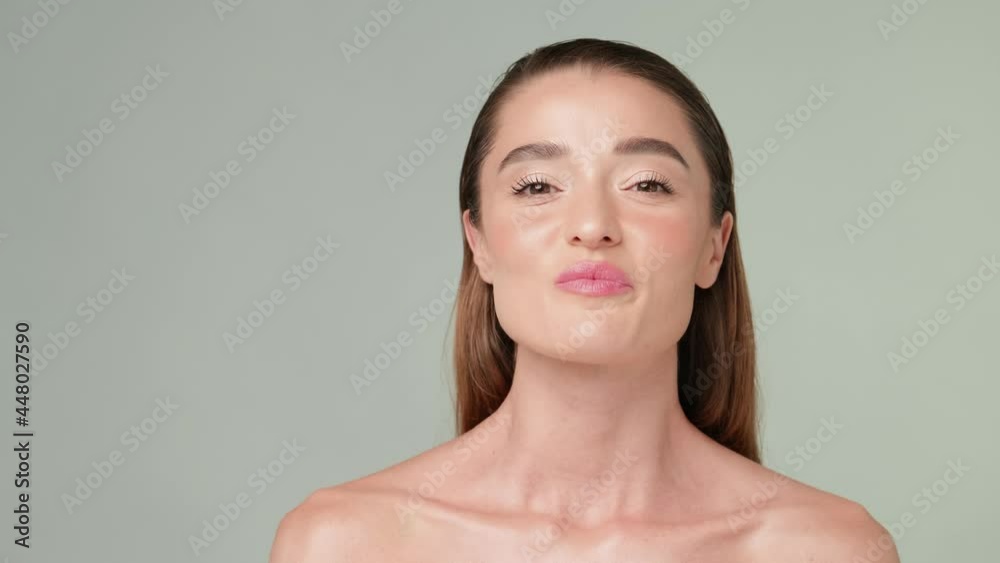 Beautiful Young Woman with Clean Fresh Skin standing over light grey background Beautiful Young Woman with Clean Fresh Skin standing over light grey background
