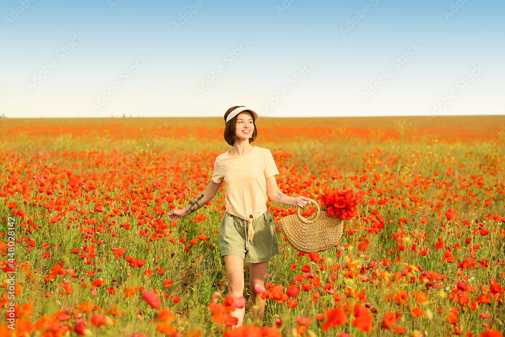 Fototapeta premium Beautiful young woman in poppy field
