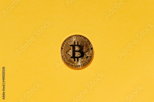Crypto currency Bitcoin physical coin on yellow background.
