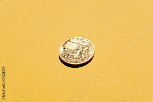 Crypto currency Bitcoin physical coin on yellow background.
