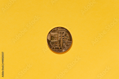 Crypto currency Bitcoin physical coin on yellow background.