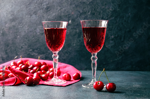 Glasses of sweet cherry wine on dark background