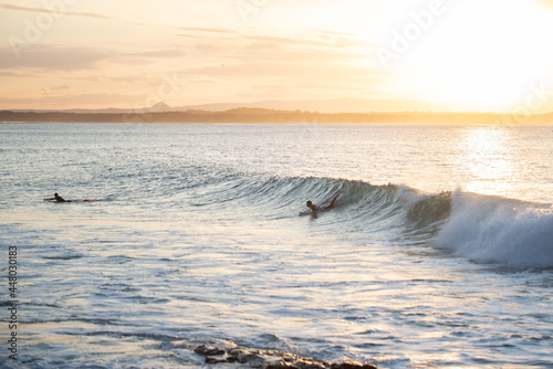 Silhouette of Surfer Catching a Wave at Sunset Time in Noosa,Queensland,Australia.Copy Space.