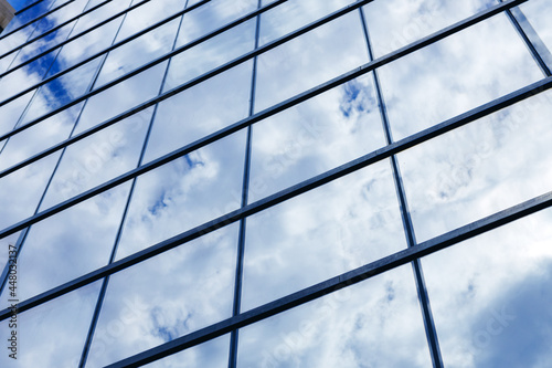 Glass skyscraper building with cloudy blue sky background