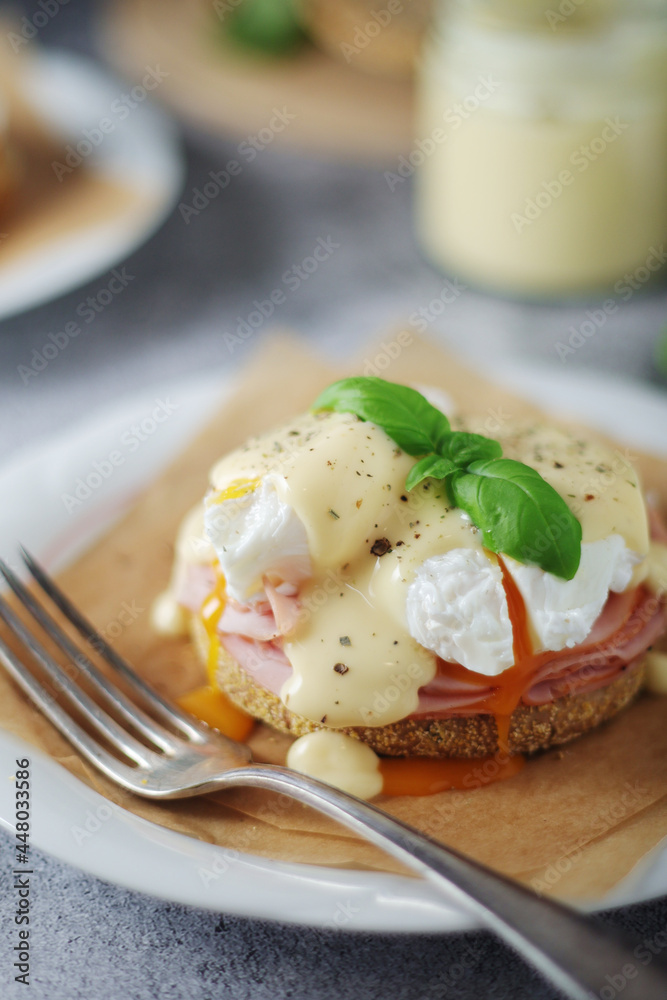 Egg benedict sandwiches - muffin with poached egg, ham and hollandaise sauce