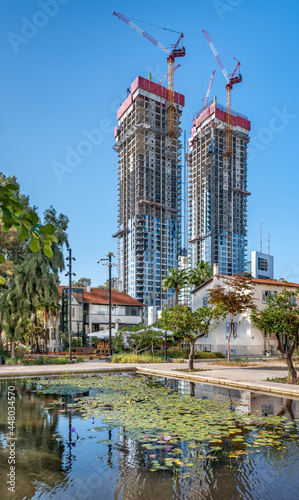 Water reflection of renovated German Templer colony buildings over under construction skyscrapers of Sarona district in Tel Aviv.