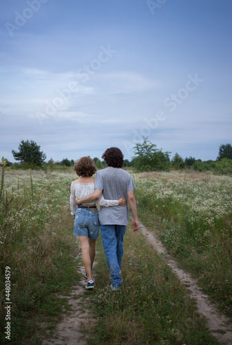 young loving couple embracing strolls in the evening in the picturesque flowering fields. boy and girl, tender feelings, romance, tenderness for each other. love concept. healthy active lifestyle