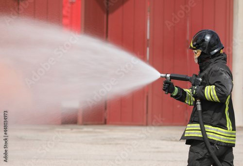 brave firefighter extinguishing a car fire using a special white flame retardant foam