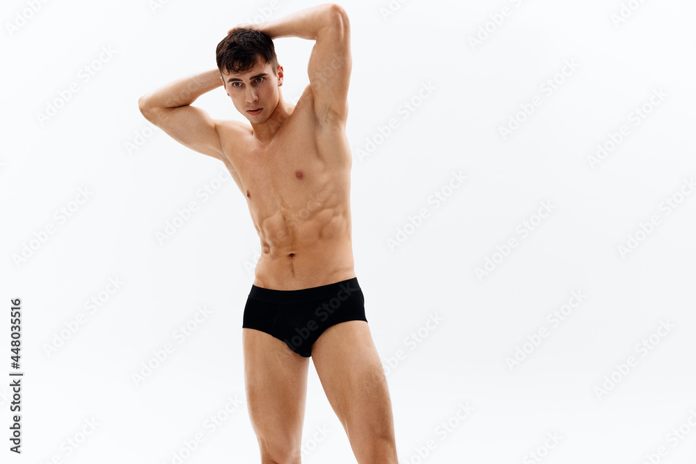 attractive man with naked muscular body in dark in shorts cropped view in light background attractive man with naked muscular body in dark in shorts cropped view in light background