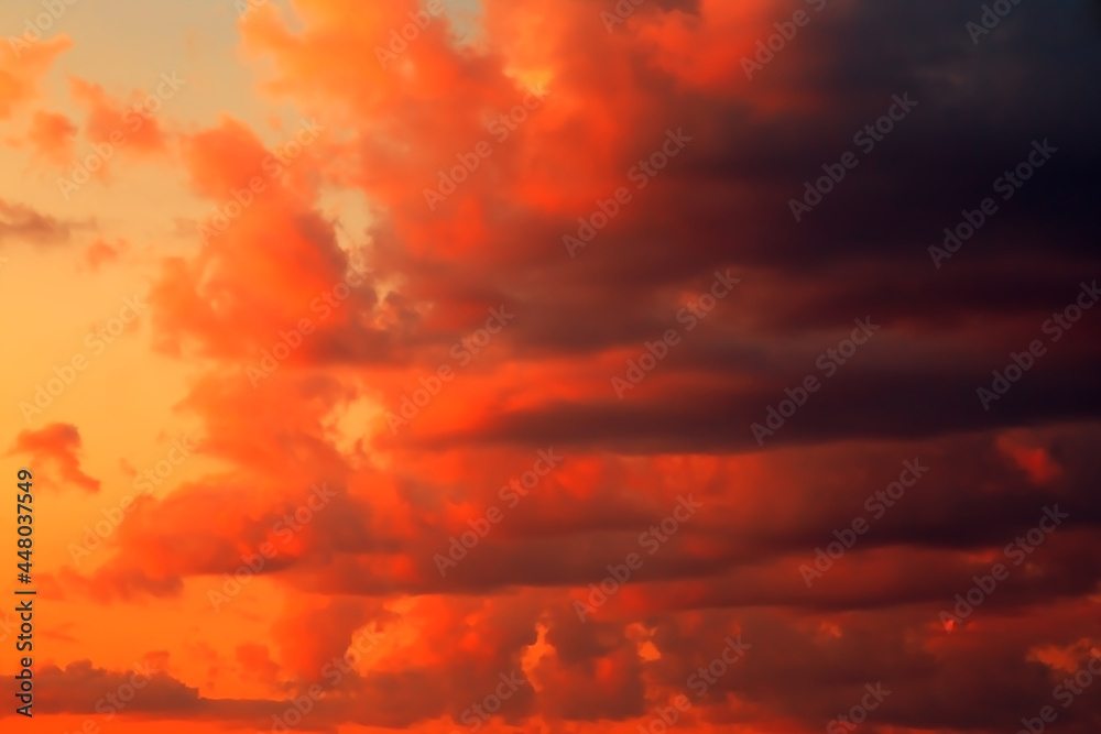 Red orange yellow epic dramatic scary mystical sunset sky with black clouds before thunderstorm storm, bright fantastic colorful sky landscape background