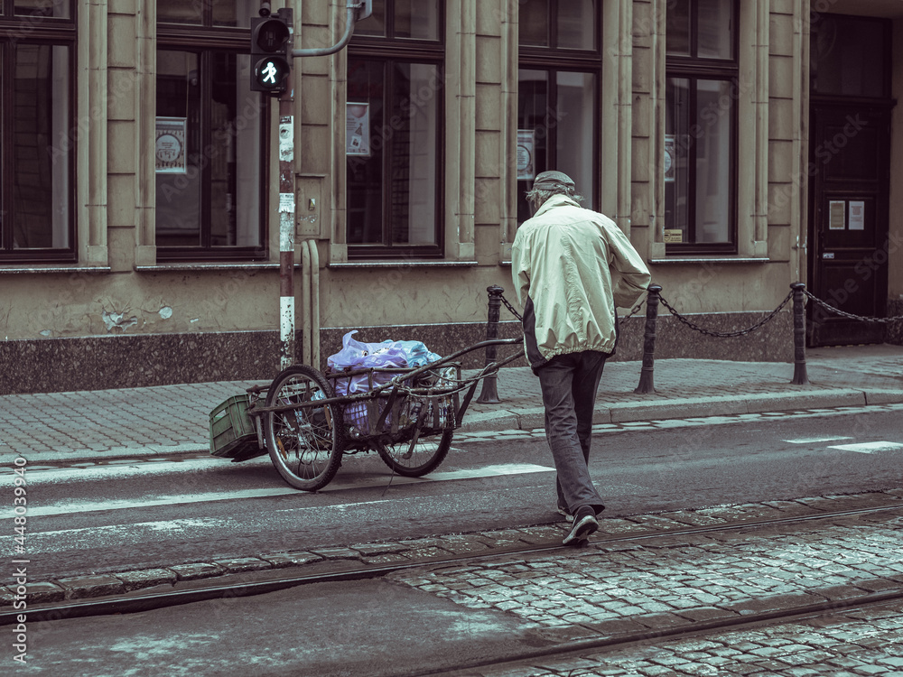 Obraz premium man pushing a cart with loads, street photography