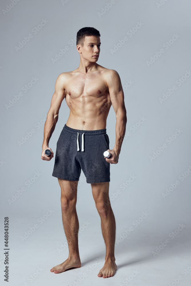 sporty man in shorts with dumbbells in hands workout exercises studio