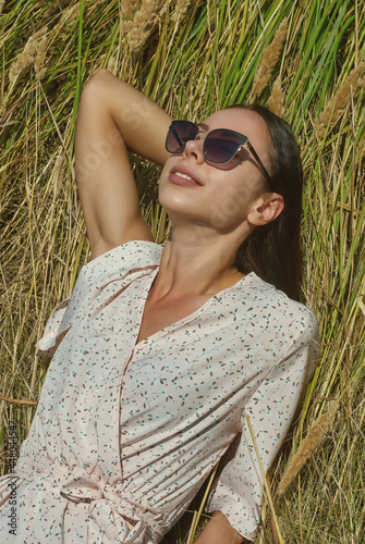 Portrait of a young woman in sunglasses. Girl in a summer dress in nature.