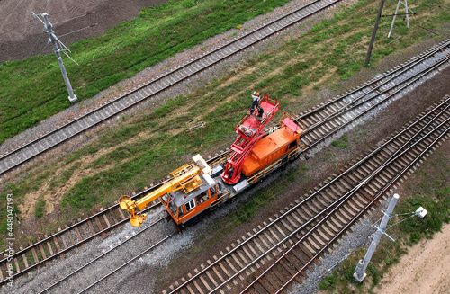 Special train with a landing crane for service and repair of electrical networks on the railway. Workers doing service work on electric lines over the rails. Railway maintenance.