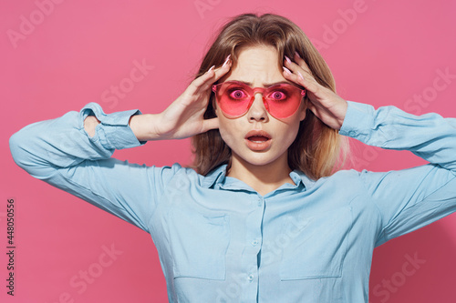 woman in blue shirt pink glasses fashion glamor posing pink background