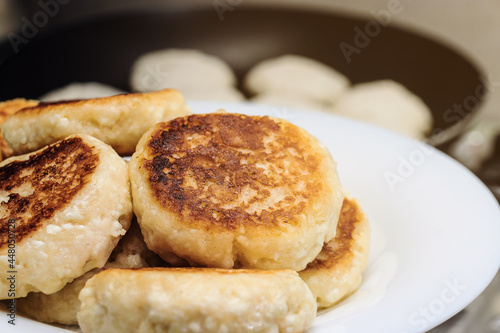 Cheese pancakes in a plate on the background of a frying pan in a close-up in the dark