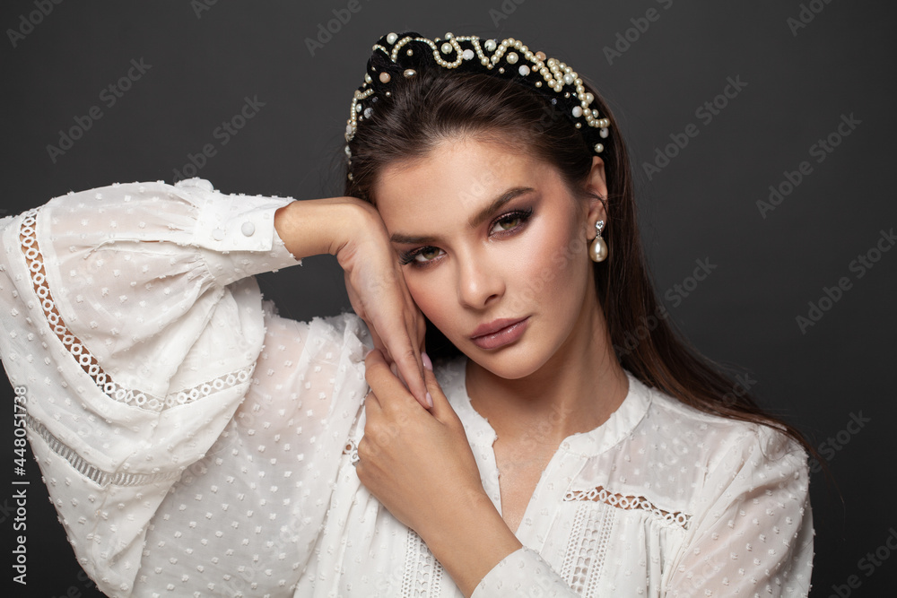 Beautiful brunette woman in black headband and pearls earring on black background Beautiful brunette woman in black headband and pearls earring on black background