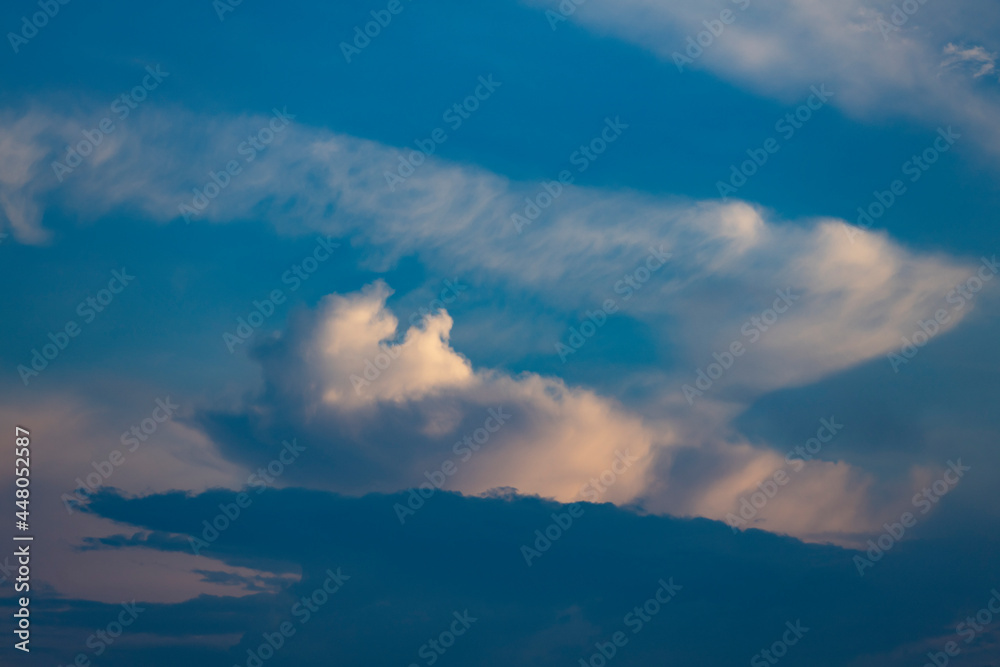 Layers of cumulus clouds and cirrus flakes in shadow with radiant vibrant colorful sunset colors. Weather conditions and climate concept. Abstract background wallpaper poster.