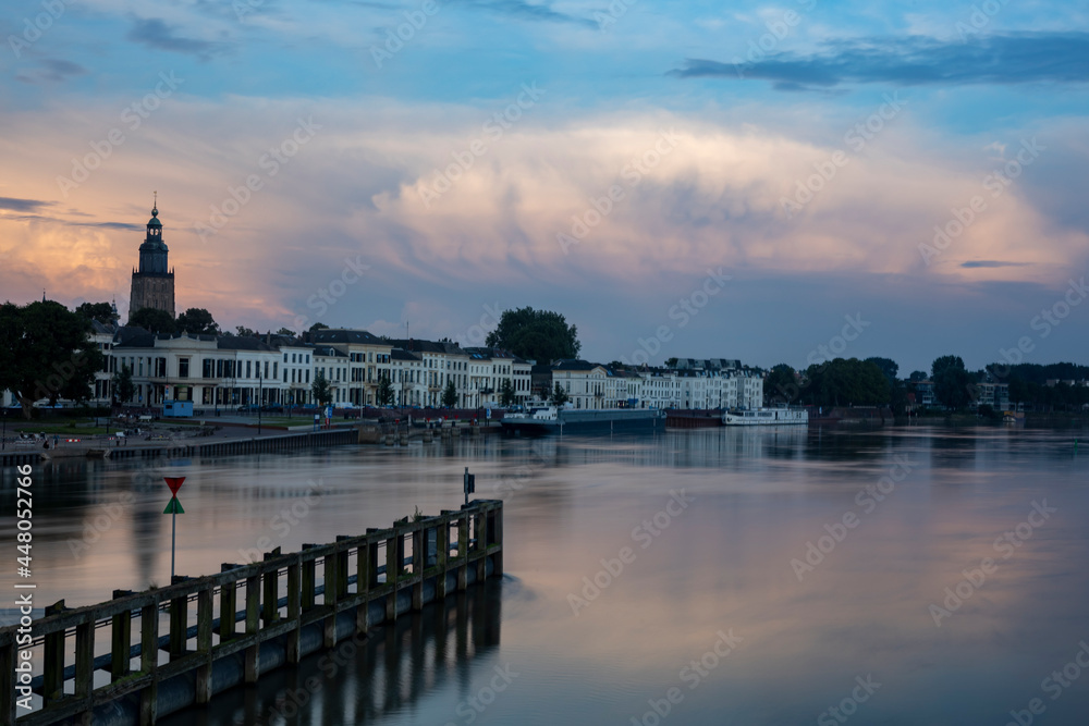 Riverscape of Zutphen in The Netherlands with large cumulonimbus rain clouds above. Dutch weather condition and climate landscape.