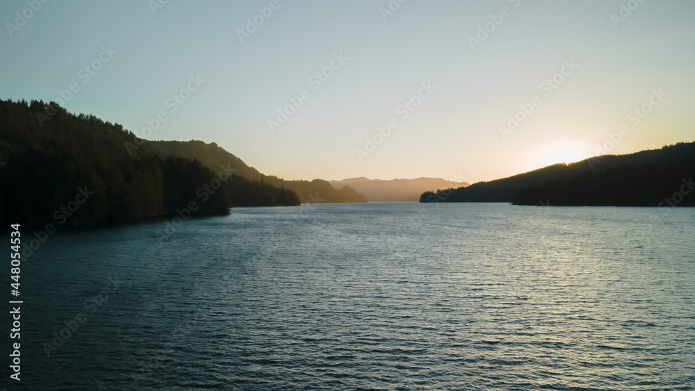 Bird's-eye view of the sunrise over the river with hilly terrain. High quality 4k footage