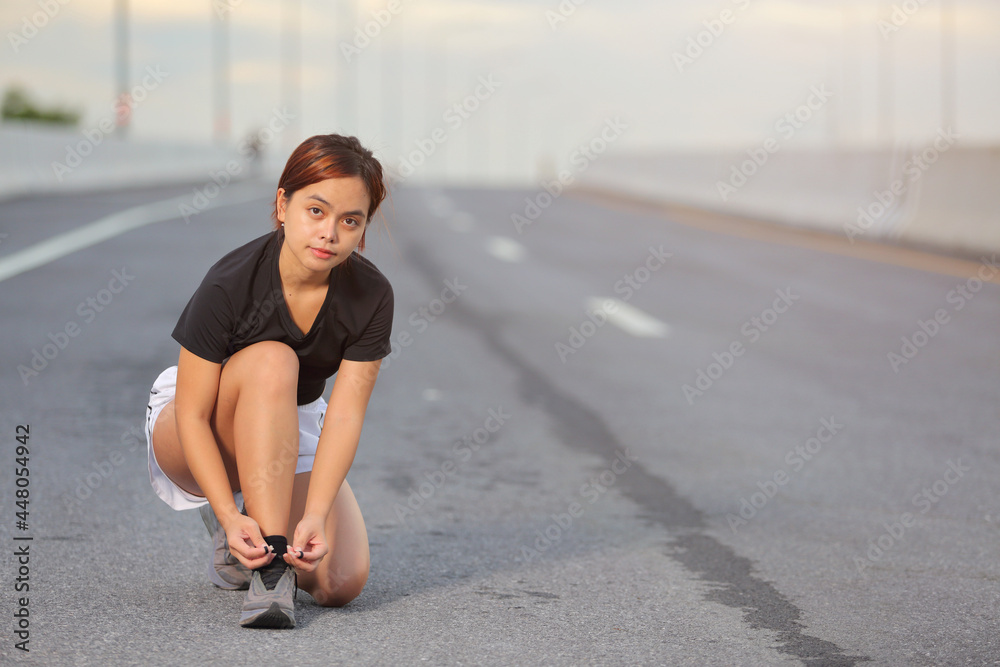 Running shoes - woman tying shoe laces. Closeup of female sport fitness runner getting ready for jogging outdoors on  the city road in the for lifestyle health.