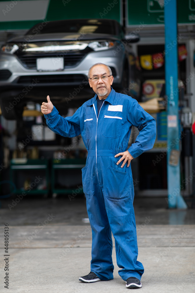 Portrait of a Asian senior mechanic working in his car service garage. Car maintenance and auto service garage concept. Portrait of a Asian senior mechanic working in his car service garage. Car maintenance and auto service garage concept.