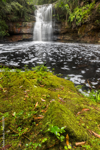 mossy ground in front of a large waterfall