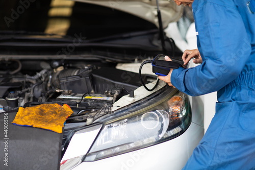 Professional car mechanic repair service and checking car engine by Diagnostics Software computer. Expertise mechanic senior man working in automobile repair garage.