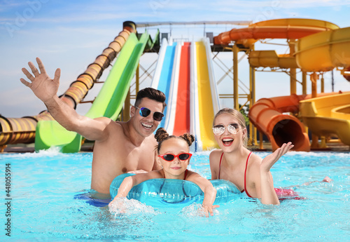 Happy family with inflatable ring in swimming pool at water park