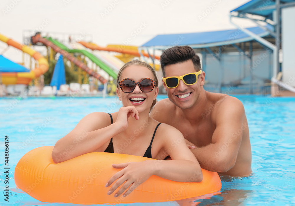 Happy couple with inflatable ring in swimming pool at water park Happy couple with inflatable ring in swimming pool at water park