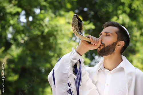 Принти на полотні Jewish man in kippah and tallit blowing shofar outdoors