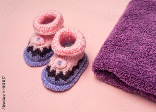 Knitted Baby booties  and towel on pink  background