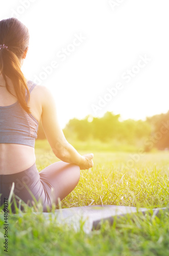 Rear view of a woman doing yoga in nature. Young woman sitting in lotus position at sunset