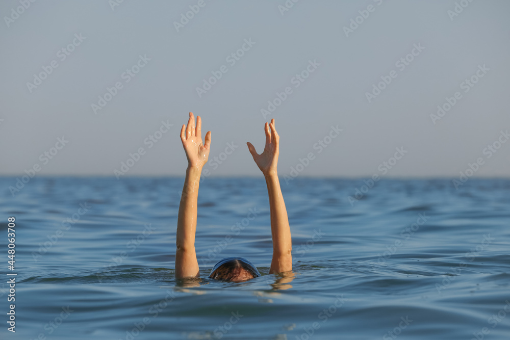 Drowning woman reaching for help in sea