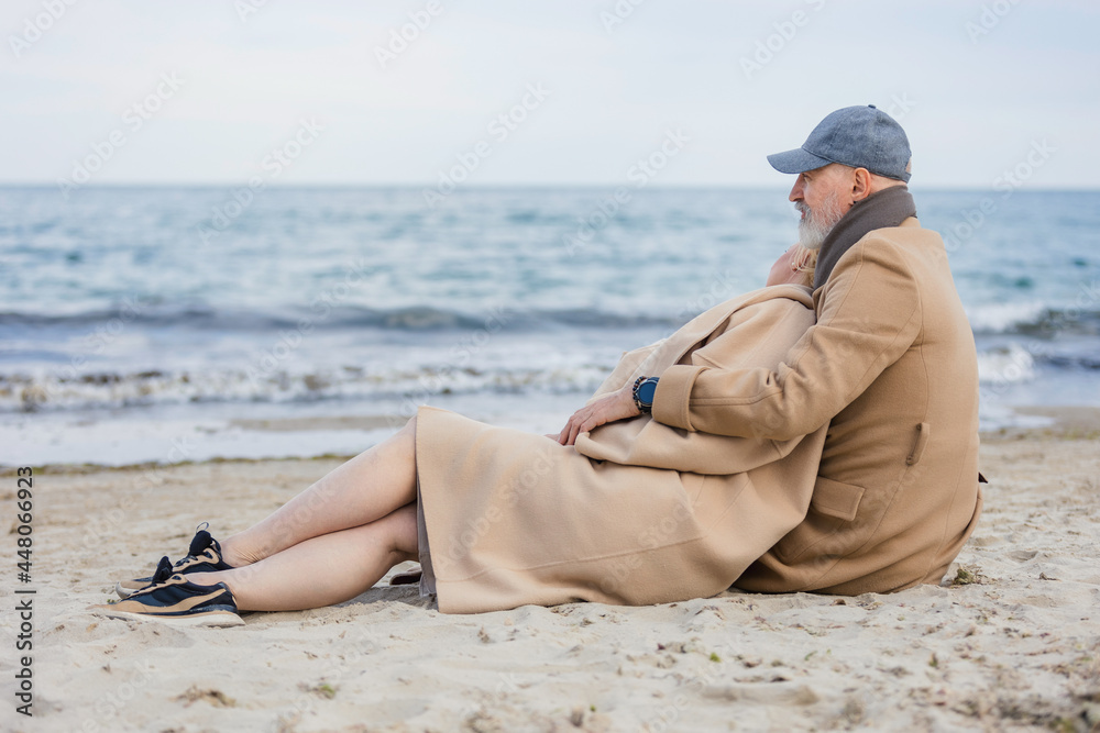 aged couple sitting on the beach near the sea