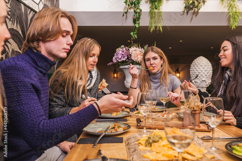 Group of young friends eating at restaurant