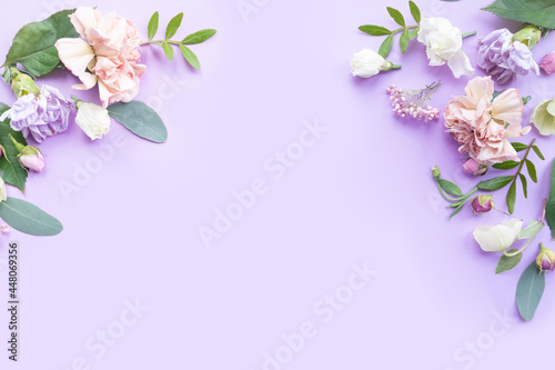 Floral frame with pink roses, white flowers, branches, leaves and petals on violet background. Flat lay, top view