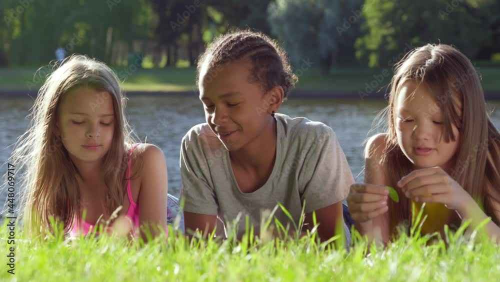 Portrait of multiracial children lying on green grass having fun together in summer park Portrait of multiracial children lying on green grass having fun together in summer park