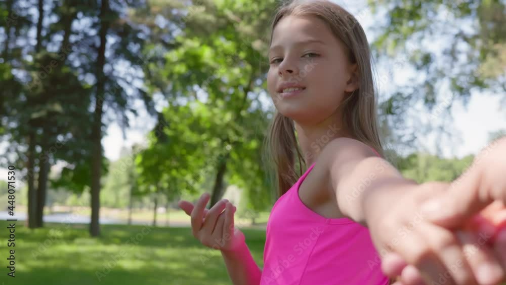 Pov shot of beautiful teen girl holding friend hand and looking at camera walking in summer park Pov shot of beautiful teen girl holding friend hand and looking at camera walking in summer park